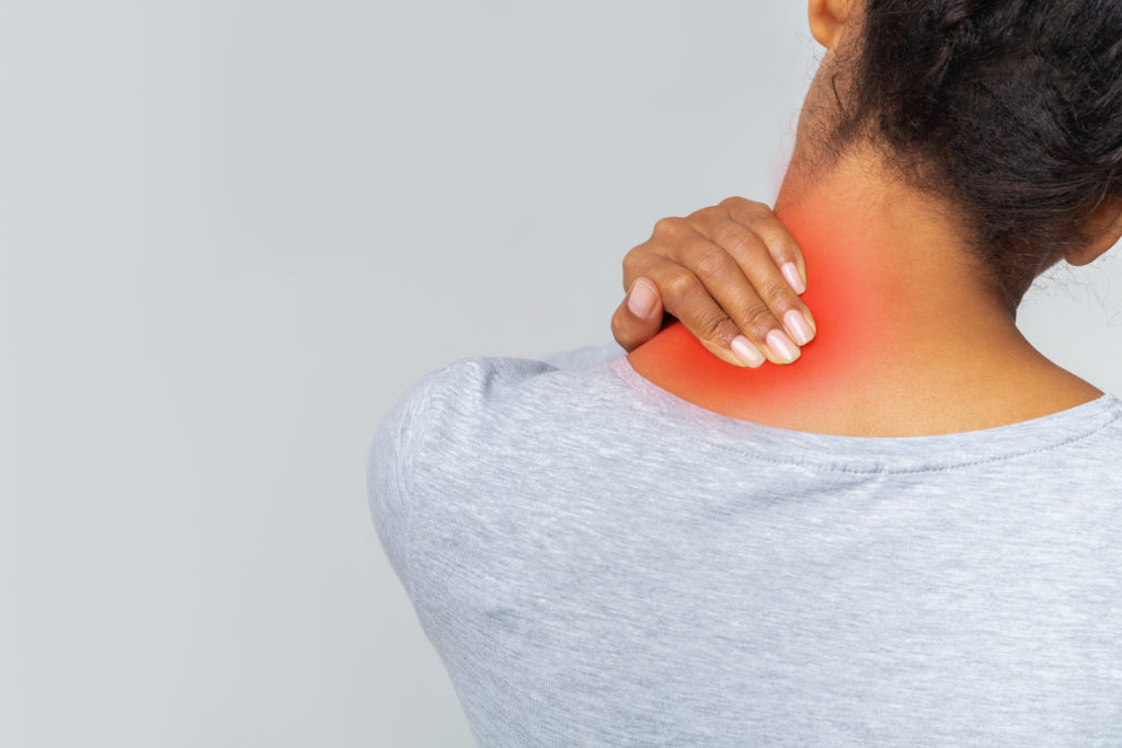 Young black woman suffering from acute pain in her neck, sore zone highlighted with red, back view, copy space