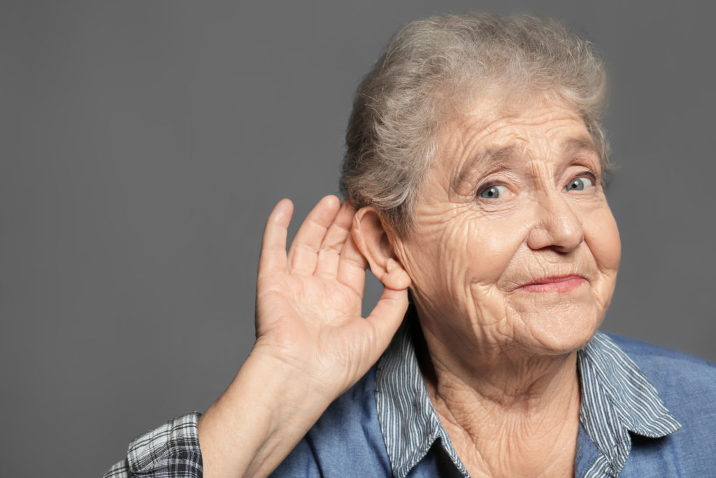 Elderly woman with hearing problem on grey background