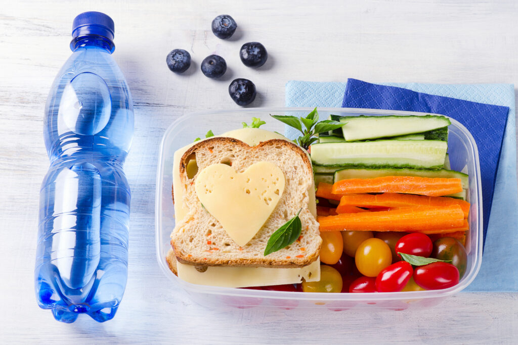 Healthy lunch box with sandwich and fresh vegetables, bottle of water. Healthy eating concept. Top view