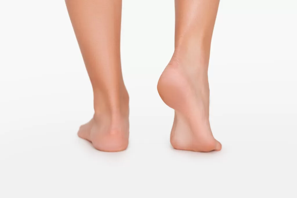 Footcare. Close up of female legs with smooth sole, white studio background